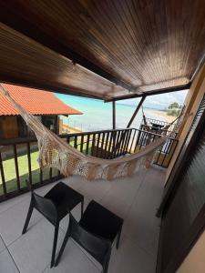 a hammock on a balcony with a view of the beach at Pousada Dra Lindalva in Maragogi