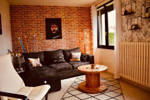 ein Wohnzimmer mit einem schwarzen Sofa und einer Ziegelwand in der Unterkunft L'AQUARELLE - Escapade normande pour 6 pers in Grugny + 34 Fotos