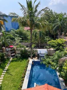a backyard with a swimming pool and a palm tree at Villa19, ECR in Tirupporūr