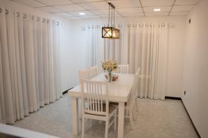 a dining room with a white table and chairs and curtains at Cinnamon Wave Villa - Thalaramba, Mirissa in Matara +6 photos