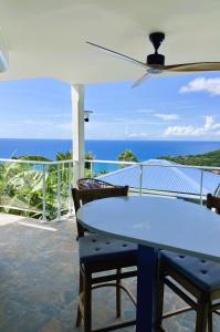 a table and chairs on a balcony with the ocean at Espace Harmonie - Gîte Indigo Deshaies in Deshaies