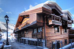 a large wooden building with a balcony on a street at Le Coeur de Courchevel in Courchevel