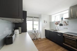 a kitchen with black cabinets and a white counter top at Tipoz'immo-Maison de la Baie vue mer accès à pied - jardin clos in Penhors