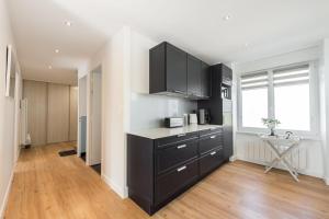 a kitchen with black cabinets and a table and a window at Tipoz'immo-Maison de la Baie vue mer accès à pied - jardin clos in Penhors