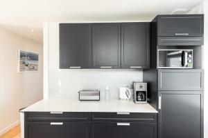 a kitchen with black cabinets and a white counter top at Tipoz'immo-Maison de la Baie vue mer accès à pied - jardin clos in Penhors