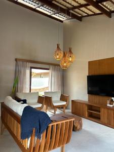 a living room with a couch and a flat screen tv at Casamares Ipioca Beach Hibiscus Maceió in Maceió