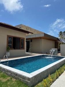a swimming pool in front of a house at Casamares Ipioca Beach Hibiscus Maceió in Maceió