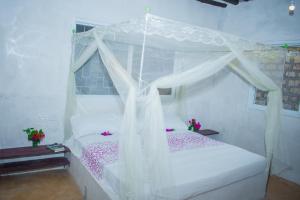 a bedroom with a white canopy bed with pink flowers at Amani Guest House Lamu in Lamu