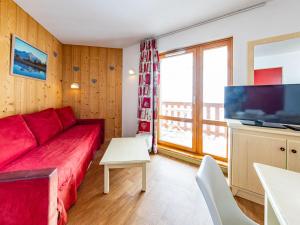 a living room with a red couch and a flat screen tv at Appartement lumineux 6 pers aux pieds des pistes, Saint-François-Longchamp - FR-1-807-30 in Saint-François-Longchamp