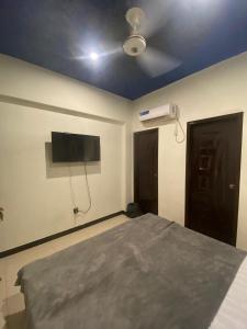 ein Schlafzimmer mit einem Bett und einem Fernseher an der Wand in der Unterkunft Beach Side Studio Apartment in Karatschi