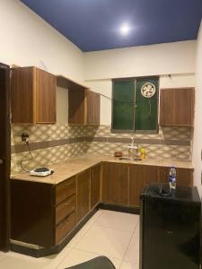 eine Küche mit Spüle und einer Uhr an der Wand in der Unterkunft Beach Side Studio Apartment in Karatschi