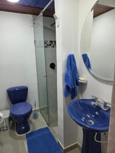 y baño con aseo azul y ducha de cristal. en Los Muiscas Tunja, en Tunja