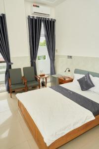 a bedroom with a large bed and two chairs at Khách sạn Thảo An in Phước Hậu (1)