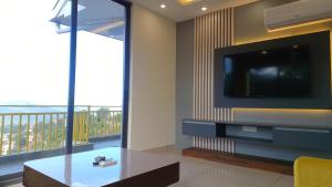 a living room with a tv and a table and a balcony at Hillshades Comfy rooms in Dagshai