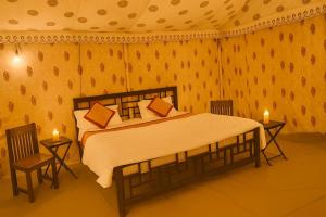ein Schlafzimmer mit einem Bett mit zwei Stühlen und zwei Kerzen in der Unterkunft Jaisalmer Villa Resort & Camp Jaisalmer in Jaisalmer
