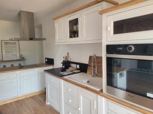 a kitchen with white cabinets and a black appliance at La Maison en Brocéliande in Paimpont