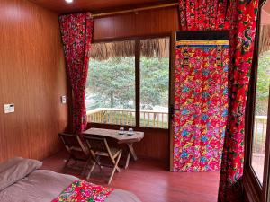 a room with a table and a window with curtains at Cát Lý Camping in Ha Giang