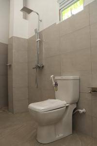 a bathroom with a white toilet and a shower at Pabalu House in Ahangama