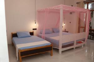 a bedroom with two beds with a canopy at Pabalu House in Ahangama
