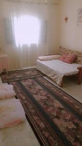 a room with two beds and a couch and a rug at غرفة هادئة للإيجار باليوم in Alexandria