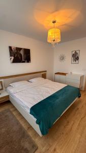 a bedroom with a large white bed and a chandelier at VENUS Studios at Coresi Mall in Braşov