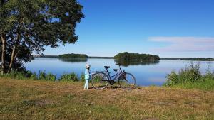 a person standing next to a bike next to a lake at Ferienwohnungen am Obersee in Linstow