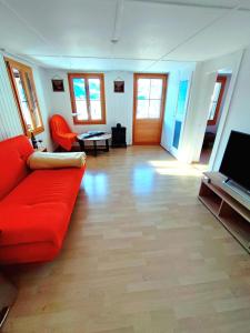 a living room with a red couch and a television at Romantic Alpine Farmhouse with Superview of Lake Near Interlaken in Sundlauenen