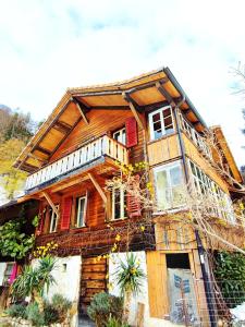 a large wooden house with red doors and windows at Romantic Alpine Farmhouse with Superview of Lake Near Interlaken in Sundlauenen