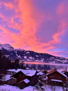 a winter sunset over a town with snow covered roofs at Romantic Alpine Farmhouse with Superview of Lake Near Interlaken in Sundlauenen
