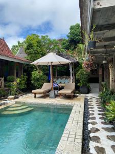 einen Pool mit einem Sonnenschirm und Stühlen sowie einem Tisch und einem Sonnenschirm in der Unterkunft Secret Wooden Cabin - Lylium Cabin Suite in Jimbaran