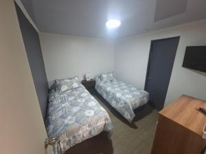 a bedroom with two beds and a television in it at Casona Eco Wing in Iquique
