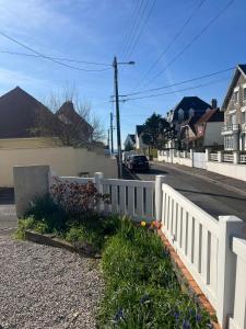 a white fence on the side of a street at Maison proche plage avec parking in Wimereux