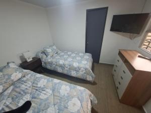 a bedroom with two beds and a dresser and a tv at Casona Eco Wing in Iquique