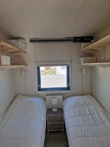 two beds in a small room with a window at Zeester in Ameland