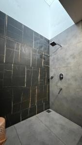 a bathroom with a shower with a stone wall at Backwater Brook in Kumarakom