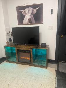 a entertainment center with a flat screen tv and a picture of a cow at Little cottage by the cabin in Springfield