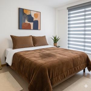 a bedroom with a large bed with a brown blanket at The Andes apartment Patio & Luxury in Cuenca