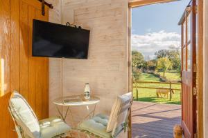 Un porche con un televisor, una mesa y sillas. en The Cosy Goose, en Charlton 5 fotos más