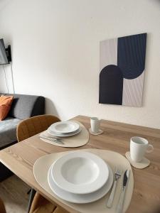 a wooden table with white plates and utensils on it at Design Vogue Apartment-Zentral-WiFi-4Personen in Metzingen