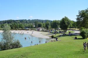un groupe de personnes nageant dans l'eau sur une plage dans l'établissement Appartement dans maison à Corbelin proche Walibi, à Corbelin