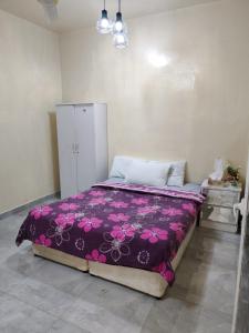 a bedroom with a bed with a purple blanket at Patio Boy Dean Guesthouse in Fujairah