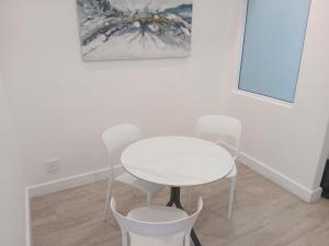 a white table and chairs in a room with a painting at 1 on albert Luxury apartment in Cape Town