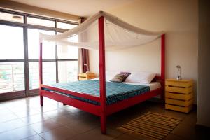 a bedroom with a red bed with a canopy at Bushpig Backpackers in Kampala