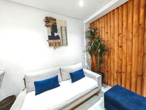a living room with a white couch and blue pillows at Le Jasmin Appartement in Dar el Haj Ahmed Souid