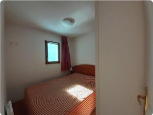 een kleine slaapkamer met een bed en een raam bij Hourquette in Bagnères-de-Bigorre