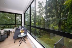 Habitación con ventanas grandes, sofá y mesa. en Stylish Scenic Oasis 2-Bedroom Suite West Van, en West Vancouver