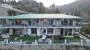 a large house with a green roof on the water at 2Bhk Home By Da Alohas Mukhteshwar in Mukteswar