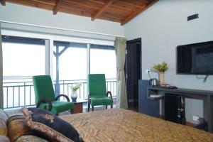 a room with a bed and chairs and a television at 2Bhk Home By Da Alohas Mukhteshwar in Mukteswar