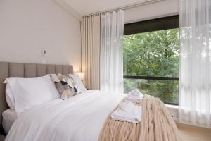 Un dormitorio con una cama blanca con una ventana. en Stylish Scenic Oasis 2-Bedroom Suite West Van, en West Vancouver