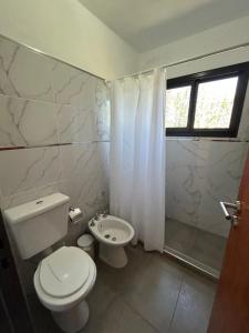 a white bathroom with a toilet and a shower at Refugio de las nubes in Las Rabonas +10 photos